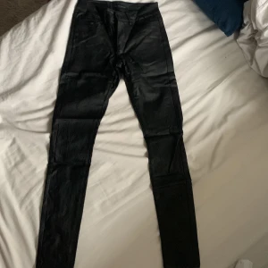 Svarta skinny skinnbyxor  från Vero Moda - Snygga svarta skinny skinnbyxor från Vero Moda i storlek XS med längd 30. Byxorna har en glansig finish, klassisk femficksdesign och smal passform som sitter tight längs benen. Perfekta för dig som gillar en stilren och modern look. (Pris kan diskuteras)