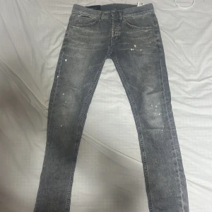 Grå dondup george - Säljer ett par grå jeans från dondup i modell george. Det är en väldigt unik design med paint splatter och snygga slitningar. Det är bland en av dom finaste jeansen jag äger och är självklart äkta. Däremot finns det en defekt i grenen som går att reparera. Priset är ej hugget i sten vid snabb affär!