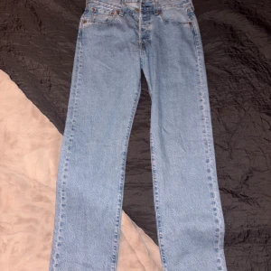 Levi's 501 ljusblå jeans W29 L32 - Säljer ett par klassiska Levi's 501 Premium jeans i ljusblå denim. Modellen har rak passform, fem fickor och knappgylf. Ikonisk läderpatch bak och snygga kontrastsömmar. Perfekta för dig som gillar tidlös och avslappnad stil.
