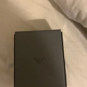 Svart klocka från Emporio Armani - Stilren svart klocka från Emporio Armani med länkarmband i metall och rund urtavla. Klockan har flera små urtavlor och tydliga indexmarkeringar. Levereras i originalask med märkestagg kvar. Perfekt accessoar för en modern look.  Fick den idag men blev inte nöjd köpt för 1760 men säljs för 1500kr kan gå ner lite beroende på pris.