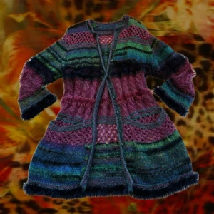 Färgglad stickad kofta med knappar - Unik och färgstark stickad kofta i lila, blått och grönt med coola mönster och fluffiga detaljer. Koftan har knappar framtill, två fickor och lång ärm. Perfekt för dig som vill sticka ut och älskar bohemiska vibes.