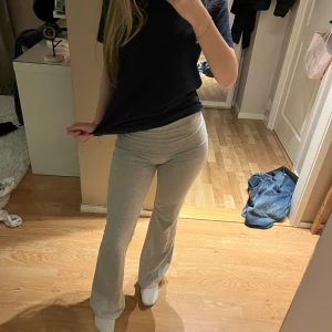 Grå bootcut mjukisbyxor - Snygga ljusgrå mjukisbyxor med bootcut och låg midja. Byxorna är i mjukt bomullsmaterial och har en bekväm passform som sitter tajt upptill och släpper ut vid benen. Perfekta för en chill och avslappnad stil.