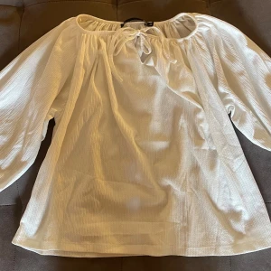 Vit offshoulder blus med knyt - Säljer en vit blus med offshoulder och knyt framtill. Blusen har vida, långa ärmar och är tillverkad i ett lätt, ribbat material som ger en luftig känsla. Perfekt för dig som gillar en avslappnad och trendig stil med romantiska vibes. PRISET GÅR ATT DISSKUTERA!!