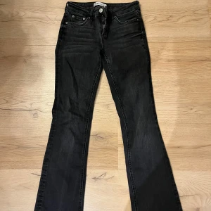 Svarta bootcut jeans från Zara - Snygga svarta jeans från Zara i storlek 34 passar 36, med klassisk femficksdesign och bootcut-ben. Jeansen har normal passform, dragkedja och knapp framtill samt bälteshällor. Materialet är jeans med en lätt tvättad look för en cool vibe. 