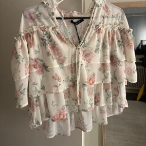 Blommig rosa blus  - Jätte gullig topp! Tyvärr var den för liten. Den är helt ny med prislapp. Den har två snören med en V- ring, och fina detaljer runt nacken! Priset diskuteras 
