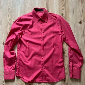 Rosa skjorta från J.Lindeberg - M - Säljer en stilren rosa skjorta från J.Lindeberg i storlek M. Skjortan har klassisk krage, långa ärmar och knäppning framtill. Perfekt för dig som vill sticka ut med färg. Materialet är mjukt och känns skönt mot huden.
