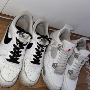 Nike Air Force 1 & Jordan 4 sneakers - Två par sneakers: ett par klassiska vita Nike Air Force 1 med svarta detaljer och snörning, samt ett par vita Nike Jordan 4 med grå mesh och röda detaljer. Båda paren har rund tå och platt sula, perfekta för en streetwear-look.