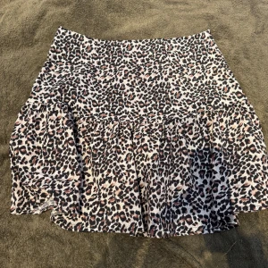 Leopard kortkjol från NLY Trend - Säljer en snygg kortkjol från NLY Trend i storlek 36 med leopardmönster. Kjolen har volangdetalj nedtill och är tillverkad i ett lätt och skönt material som ger en cool vibe. Perfekt för dig som gillar att sticka ut med djurmönster.