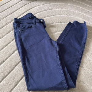 Mörkblå skinny byxor från KappAhl - Snygga mörkblå byxor från KappAhl i storlek 38. Modellen är skinny med klassisk femficksdesign och dragkedja med knapp. Materialet är mjukt och stretchigt, vilket gör dem riktigt bekväma att bära. Perfekta för dig som gillar en smal siluett.