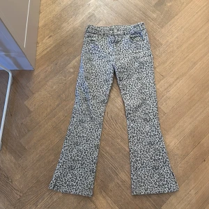 Leopardmönstrade bootcut byxor Zara - Snygga bootcut byxor från Zara i storlek 152, med grått leopardmönster. Byxorna har klassisk femficksdesign och är tillverkade i ett mjukt bomullstyg med lite stretch. Perfekta för dig som vill sticka ut med ett coolt mönster och trendig passform.