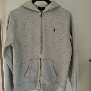 Grå ziphoodie från Polo Ralph Lauren - Snygg grå ziphoodie från Polo Ralph Lauren i storlek XL, men skulle säga att tröjan sitter som en S-M. Väldigt bra skick
