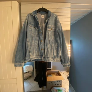 Ljusblå jeansjacka från Lee - Säljer en klassisk ljusblå jeansjacka från Lee med bronsfärgade knappar och två bröstfickor med lock. Jackan har en avslappnad passform och är perfekt att slänga över en hoodie eller t-shirt. Tidlös modell som funkar året runt!!