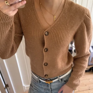 Beige kofta från Les Coyotes de Paris - Säljer en ribbstickad beige kofta från Les Coyotes de Paris. Koftan har v-ringning, stora knappar framtill och är tillverkad i en mjuk ullblandning. Passar som en XS och köpt för 2200kr