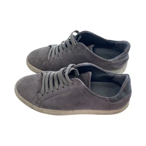 Grå Axel Arigato skor - Snygga grå sneakers från Axel Arigato i mjuk mocka med klassisk låg profil och rund tå. Inte helt nya men fungerar fortsatt alldeles perfekt! Perfekta för dig som gillar minimalistisk och stilren design med en lyxig känsla. Storlek 41 HÖR AV ER VID FRÅGOR ELLER FUNDERINGAR!