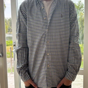 Rutig skjorta från Ralph Lauren M - Klassisk rutig skjorta från Ralph Lauren i vitt, blått och grönt. Skjortan har knappar framtill, button-down krage och broderad logga på bröstet. Tillverkad i mjuk bomull och har långa ärmar. Perfekt för en stilren och avslappnad look.