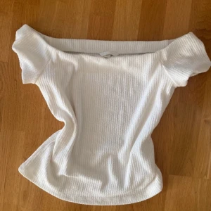 Vit ribbad offshoulder topp - Snygg vit ribbad topp med offshoulder-design och korta ärmar. Mjuk & Stretchig och passar till många outfits🎀