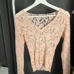 Ljusrosa spetsblus från Gina Tricot - Superfin ljusrosa blus i spets från Gina Tricot. Blusen har lång ärm, v-ringning och är helt täckt av blommigt spetsmönster. Använd EN gång. Sann i storlek
