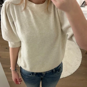 Beige stickad tröja med puffärm - Superfin beige stickad tröja från Vero moda med korta puffärmar och ribbade muddar. Endast använd en gång
