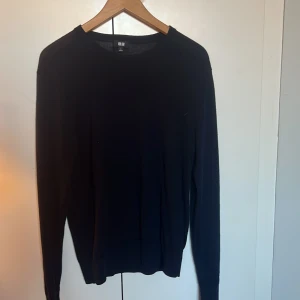 Marinblå stickad tröja från Uniqlo - En stilren marinblå stickad tröja från Uniqlo i storlek S. Tröjan har rund halsringning och långa ärmar, perfekt för lager-på-lager eller som den är. Enkel och klassisk design som funkar till det mesta.