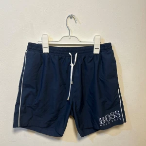 Mörkblå badbyxor från Hugo Boss - Badbyxor i nyskick, endast prövade men tyvärr för små och köpta på outlet. Inga skador eller fläckar. 