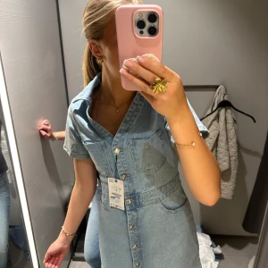 Ljusblå jeansklänning med knappar - Säljer en ljusblå jeansklänning från Monki med kort ärm, v-ringning och stora bröstfickor. Klänningen har markerad midja och knappar hela vägen framtill. Perfekt för dig som gillar denim och vill ha en cool och avslappnad look. pris går att diskutera!❤️
