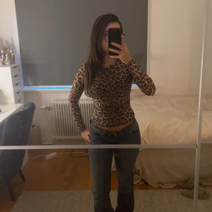 Leopardmönstrad långärmad topp - Säljer en tight långärmad topp med leopardmönster i bruna och svarta toner. Toppen har rund halsringning och är figurnära i modellen, perfekt för dig som vill sticka ut lite extra. Materialet känns stretchigt och följsamt.