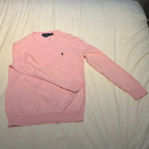 Rosa tröja från Polo Ralph Lauren - Snygg rosa långärmad tröja från Polo Ralph Lauren i slim fit-modell. Tröjan har rund halsringning och klassisk broderad logga på bröstet. Perfekt för dig som gillar stilrena och fräscha plagg med en skön stil 