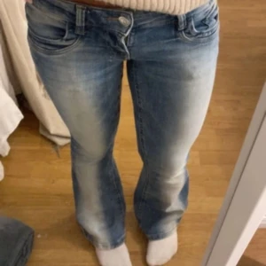 Blå bootcut jeans från Gina - Snygga blå jeans med bootcut-modell och slitna detaljer på låren. Jeansen har låg midja och klassisk femficksdesign. Perfekta för en avslappnad och trendig look.