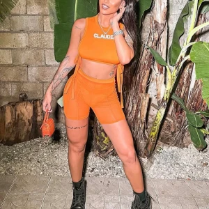 Orange cykelshorts och topp - Säljer ett par orange cykelshorts med hög midja och stretchigt material ihop med en topp. Outfiten har en festlig vibe och sitter figurnära, perfekta för en trendig och snygg look. 
