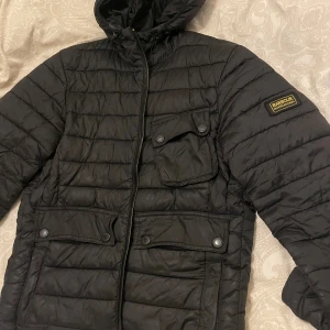  Barbour International Ouston Hooded Quilt Jacket  - Säljer min barbour jacka HERR  i färgen svart, funkar för kvinnor med.  Jackan är i [mycket fint skick använd men välskött och passar perfekt till höst och vnter Storlek M   Nypris ca 2 800 kr Säljer för 1050kr men kan gå ner vid snabb affär! 