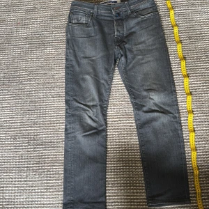 Grå jeans från Jacob Cohen - Snygga grå jeans från Jacob Cohen med klassisk femficksdesign och bruna detaljer på bakfickan. Jeansen har raka ben och subtila slitningar för en cool look. Perfekta för dig som gillar stilrena och bekväma jeans med exklusiv känsla.                                         Orginal pris: 4299kr                                                            Längd: 100-105cm.                                                                   Passar: 170-175cm