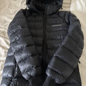Svart Peak Performance dunjacka med huva - Säljer en svart dunjacka från Peak Performance i storlek 170. Jackan är inprincip helt ny använd ca 3 gånger och säljer den då den tyvärr var för stor. Skriv om ni vill ha fler bilder på jackan. Köpt för 2999kr💕