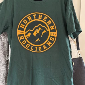 Grön Northern Hooligans t-shirt - Mörkgrön t-shirt från Northern Hooligans med stort gult tryck framtill. använd fåtal gånger, säljes pga att den inte används