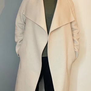 WERA Coat Cloud Ullkappa med bälte och bred krage. Stl 36 - Endast använd ett fåtal gånger.Slutsåld överallt Nypris 2499:-  Fin trench coat från märket WERA i ull - med bred, snygg krage och knytskärp i midjan. Lång modell med raka ärmar. Perfekt för dig som gillar en clean och modern look. Materialet är mjukt och känns lyxigt.  • Ullkappa med krage • Stängs med skärp i midjan • Sidfickor 