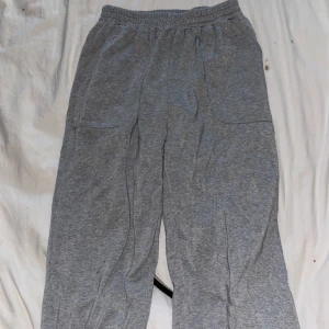 Grå mjukisbyxor med resårmidja - Grå mjukisbyxor i bomull med resår i midjan och raka ben. Byxorna har två sidofickor och en avslappnad passform, perfekta för chill dagar eller när du vill vara bekväm. Klassisk look utan synliga loggor eller detaljer.