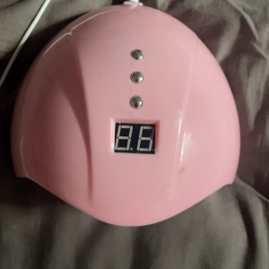 UV LED Nagellampa med timer - Rosa UV LED nagellampa med digital timer (30/60/99 sekunder). Flera LED-lampor för jämn härdning av gelnaglar. USB-anslutning. Mindre repor och lätt slitage syns, men fungerar utmärkt.