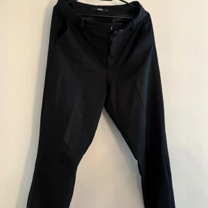 Svarta kostymbyxor från BikBok - Stilrena svarta kostymbyxor från BikBok med klassisk passform och dragkedja framtill. Byxorna har hällor för bälte och raka ben, perfekta för en clean och snygg look. Materialet känns mjukt och följsamt.