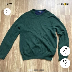 Mörkgrön stickad tröja från Polo Ralph Lauren - Snygg mörkgrön stickad tröja från Polo Ralph Lauren med rund hals och diskret broderad logga på bröstet. Tröjan har långa ärmar och ribbade muddar vid ärmslut och nederkant. Perfekt för dig som gillar klassisk stil.