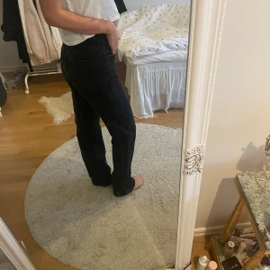 Svarta raka jeans med hög midja - Säljer ett par svarta jeans med hög midja och raka ben. Jeansen har klassisk femficksdesign och stängs med knapp och dragkedja. Perfekta för dig som gillar en enkel och stilren look.