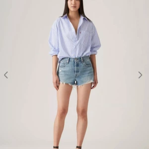 Levi's blå jeansshorts med fransig kant - Säljer ett par klassiska blå jeansshorts från Levi's med hög midja och rå, fransig kant nertill. Shortsen har fem fickor, bälteshällor och Levi's ikoniska läderpatch bak.  Ordinarie pris 700 kr🤗