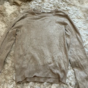 Beige stickad tröja från ONLY - En enkel och stilren beige stickad tröja från ONLY. Tröjan har rund halsringning, långa ärmar och ribbade muddar vid ärmslut och nederkant. Perfekt för lager-på-lager och passar till allt.