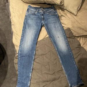 Blå Replay Anbass jeans slim fit - Säljer ett par blå Replay Anbass jeans med slim passform och klassisk femficksdesign. Jeansen har ljusa slitningar framtill och bak, samt Replay-lapp på bakfickan. Perfekta för dig som gillar en smal siluett och snygg tvätt. Dem har även en liten fläck som inte går bort