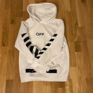 Vit Off-White hoodie med tryck - Säljer en vit hoodie från Off-White med svarta grafiska tryck på ärmar, fram- och baksida. Klassisk huva och känguruficka framtill. Stora pilar och texten 'SEEING THINGS' på ryggen. Perfekt för dig som gillar streetwear och vill sticka ut. den är s men passar mer som xs pris kan diskuteras vid snabb affär 
