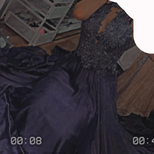 Lång lila  bröllop/balklänning med spetsdetaljer 38/40 - Säljer en elegant lång lila bröllop/balklänning med hög hals och v-ringning. Klänningen har vackra broderade spetsdetaljer upptill och en flowy kjol i satinliknande material. Liten skada på ryggen men går att fixa. Passar även storlek 38 , använd 1 gång bara