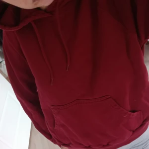 Röd hoodie från Stay, storlek S - Säljer en röd hoodie från Stay i storlek S. Tröjan har huva med snörning, magficka och ribbade muddar vid ärmslut och nederkant. Perfekt för dig som gillar en enkel och klassisk look. Materialet är mjukt och skönt, troligtvis bomull eller bomullsblandning. Mer vinröd i färgen än på bilden