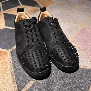 Chirstian Louboutin skor svarta - Säljer ett par svarta skor från Christian Louboutin med mattsvarta nitar på tån och klassisk röd sula. Skorna har snörning och är tillverkade i mocka med detaljer i skinn. .