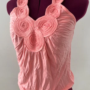 Rosa halterneck topp från Vila - Supersöt rosa halterneck topp från Vila med unika cirkeldetaljer framtill och knytning i nacken. Tunt och mjukt material som känns luftigt, perfekt för varma dagar. Snyggt rynkad effekt och feminin design som sticker ut.