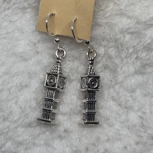Silverfärgade örhängen Big Ben - Unika örhängen i silverfärgad metall med detaljerade hängen formade som Big Ben. Perfekta för dig som älskar London eller vill ha ett statement-smycke med cool arkitekturlook.