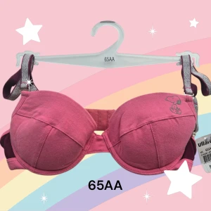 Rosa Snobben-bh 65AA - Söta behå med Snoopy-tryck i rosa. Den har glittriga axelband och är tillverkade i mjuk bomull (95%) och elastan (5%). Kuporna är formade och har en enkel, stilren design med kontrastfärgade detaljer på banden och Snobben-tryck på ena kupan. Axelbanden är avtagbara. Urtagbara inlägg i kuporna. Perfekt för dig som gillar gulliga och bekväma underkläder. Är nya med orginallapparna på. Kommer från konkurslager. Rabatt vid köp av flera. Finns fler storlekar, bara fråga.