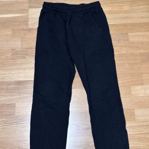 Svarta mjukisbyxor från Kappahl - Svarta mjukisbyxor från Kappahl i storlek 164. Byxorna har resår och snörning i midjan samt två sidofickor. Perfekta för chill dagar eller när du vill ha det extra bekvämt. Klassisk rak passform och mjukt material.